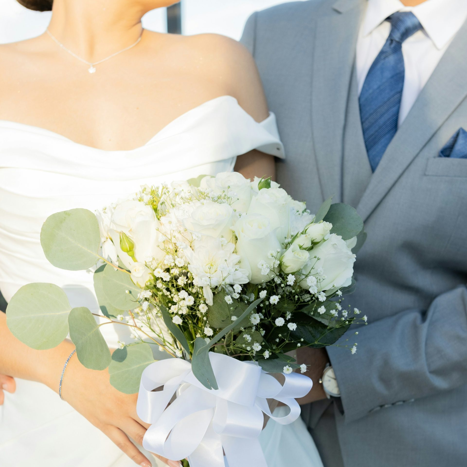 Bride and groom holding a white rose bouquet